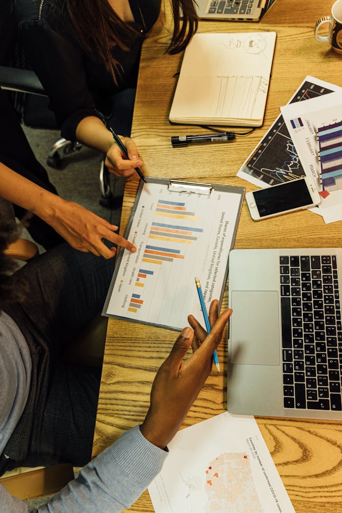 team-03 Team members analyzing business charts and reports in an office setting around a wooden table.