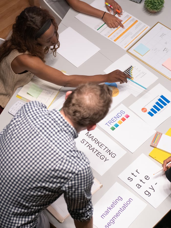 who-we-are Team discussing marketing strategies in a modern office setting with charts and documents.