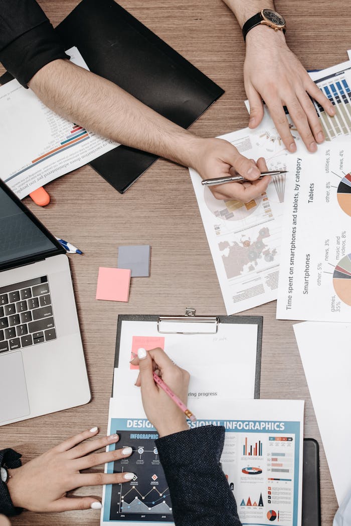 who-we-are Overhead view of a team collaborating on infographic design with charts and laptops.